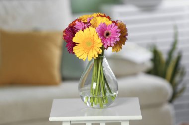 Bir buket güzel Gerbera çiçeği, cam vazoda, beyaz masada.