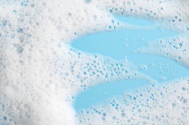 Açık mavi arka planda köpüklü Deterjan köpüğü, üst görünümde
