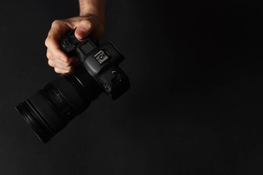Siyah arka planda profesyonel kamerası olan bir fotoğrafçı. Metin için boşluk