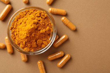 Zerdeçal kapsülleri ve bej arka planda toz, düz bir zemin. Metin için boşluk