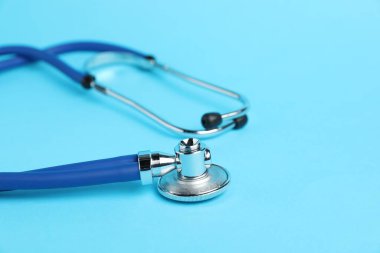 Açık mavi arka planda steteskop, yakın plan. Metin için boşluk