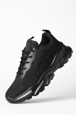 Beyaz arka plana karşı havada şık siyah spor ayakkabısı