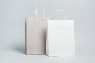 Açık gri arka planda iki boş alışveriş torbası. Tasarım için model