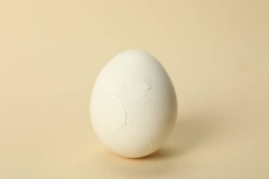 Bej arka planda kırık kabuklu bir yumurta, yakın plan.