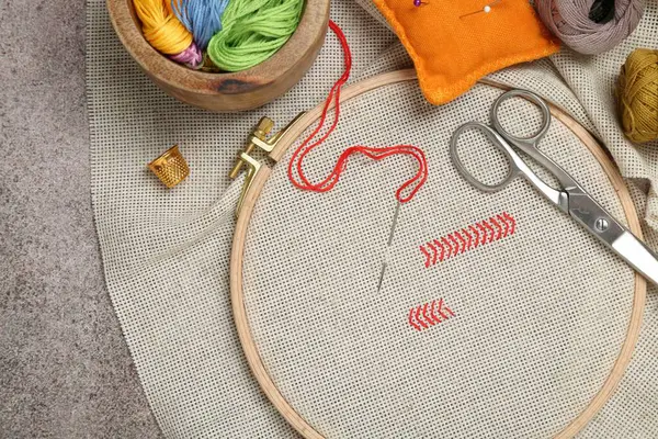 Nakış ve farklı dikiş aksesuarları gri masada, düz yerde.