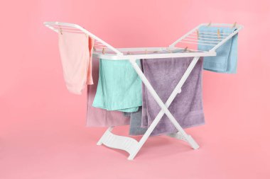 Açık pembe arka planda temiz çamaşırlı kuru askı.