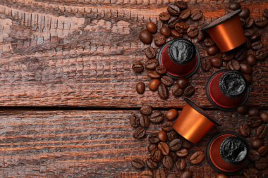 Kahve kapsülleri ve fasulyeler ahşap masada, düz yerde. Metin için boşluk