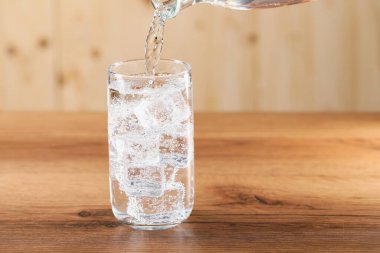 Tazeleyici soda bardağa dökülüyor ahşap masada, yakın plan.