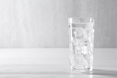 Soda tazeleniyor, beyaz ahşap masada buzlu buzlar var, metin için yer var.
