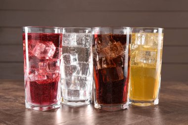 Farklı aromalı soda ve ahşap masada buz küpleri.
