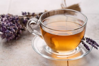 Cam bardakta Aromatik lavanta çayı ve beyaz fayanslı masada kuru çiçekler, yakın plan.
