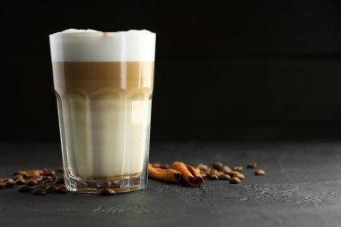 Bardakta latte macchiato, siyah masada kahve çekirdekleri ve tarçın, yakın plan. Metin için boşluk