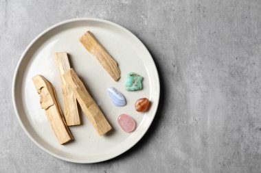 Palo Santo çubukları ve değerli taşlar gri masada, üst manzara. Metin için boşluk