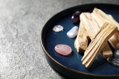 Palo santo sopaları ve değerli taşlar gri masada, yakın plan.