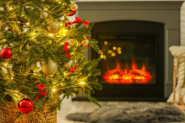 Evdeki şöminenin yanında güzel dekore edilmiş Noel ağacı, yakın çekim. Bokeh etkisi