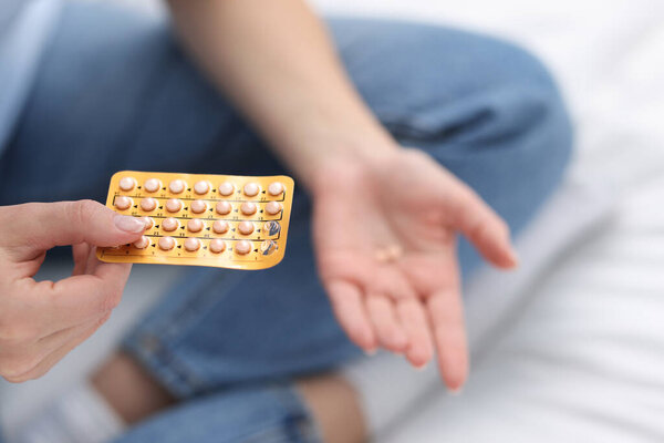 Woman with contraceptive pills on bed, closeup