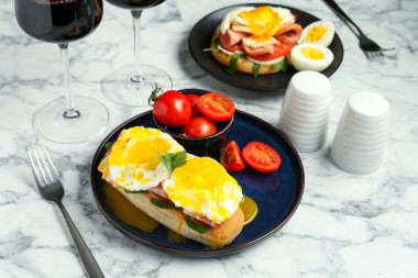 Lezzetli bir kahvaltı. Haşlanmış yumurta, pastırma, çörek ve domates beyaz mermer masada servis edilir.