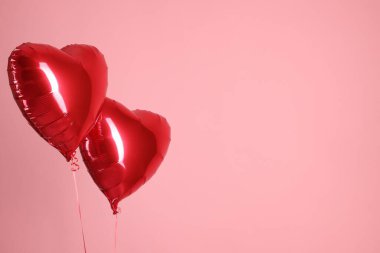 Pembe arka planda iki kırmızı kalp şeklinde balon, mesaj için boşluk. Sevgililer Günün kutlu olsun.