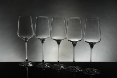 Gri arkaplana karşı ayna yüzeyinde birçok boş bardak