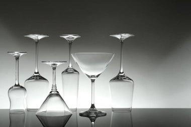 Gri arkaplana karşı ayna yüzeyinde birçok boş bardak