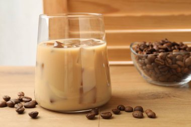 Bardakta kremalı kahve likörü ve ahşap masada fasulye, yakın plan.