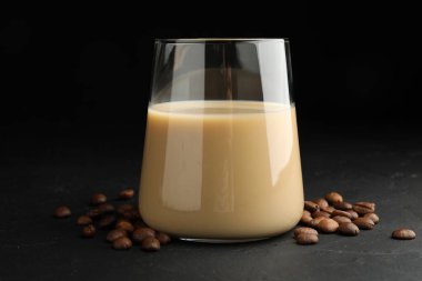 Bardakta kremalı kahve likörü ve siyah masada fasulye.