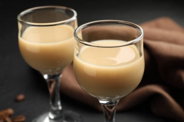 Bardakta kremalı kahve likörü ve siyah masada fasulye, yakın plan.