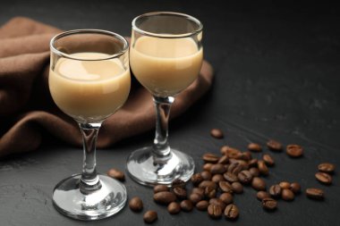 Bardakta kremalı kahve likörü ve siyah masada fasulye, yakın plan.