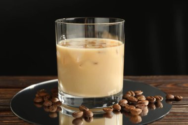 Bardakta kremalı kahve likörü ve ahşap masada fasulye, yakın plan.