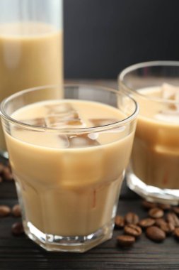 Bardakta kremalı kahve likörü ve ahşap masada fasulye, yakın plan.