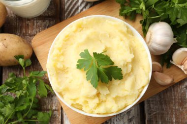 Delicious mashed potato with parsley served on wooden table, flat lay