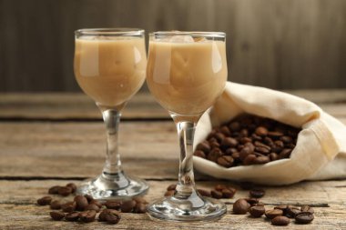 Bardakta kremalı kahve likörü ve ahşap masada fasulye, yakın plan.