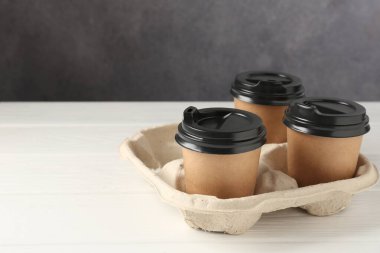 Kağıt kahve bardakları beyaz ahşap masadaki karton tutacakta. Metin için boşluk