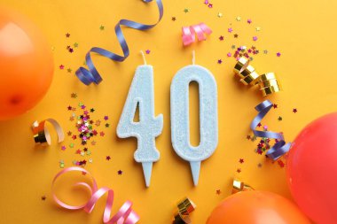 40. yaş günü. Turuncu arka planda numara şekilli mumlar ve parti dekoru, düz uzanma
