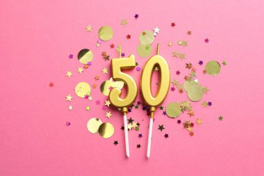 50. yaş günü. Pembe arkaplandaki mumlar ve konfetiler düzdü.