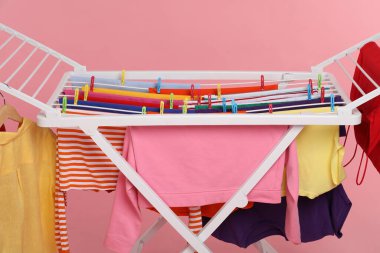 Açık pembe arka planda temiz çamaşırları olan kuru askı, yakın plan.