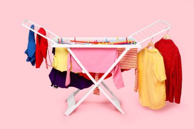 Açık pembe arka planda temiz çamaşırlı kuru askı.