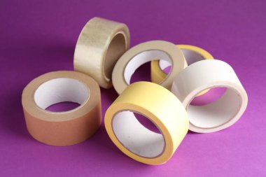 Mor arka planda farklı yapışkan bantların ruloları, yakın plan