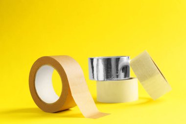 Sarı arka planda farklı yapışkan bantların ruloları