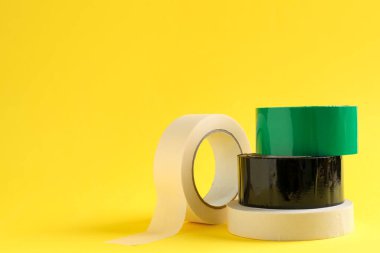 Sarı arkaplanda farklı yapıştırıcı bantların ruloları, metin için boşluk