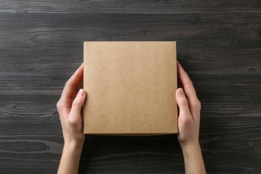 Koyu ahşap arka planda, boş karton kutulu kadın, üst manzara. Tasarım için model