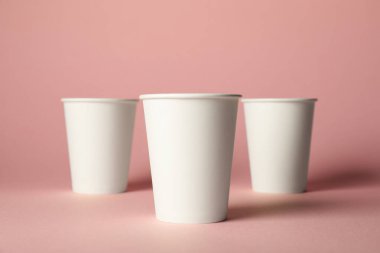 Pembe arka planda kağıt bardaklar. Tasarım için model