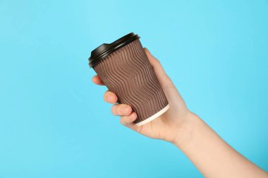 Açık mavi arka planda kağıt bardak tutan kadın, yakın plan. Tasarım için model