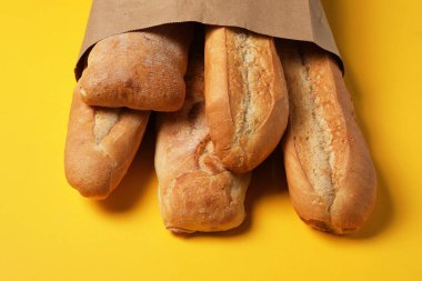 Sarı arka planda taze baget ve ciabatta torbası, yakın plan.