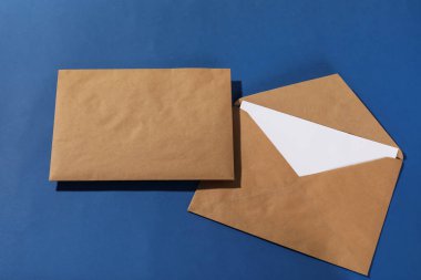 Mavi arka planda harf olan Kraft kağıt zarfları, üst görünüm. Tasarım için model