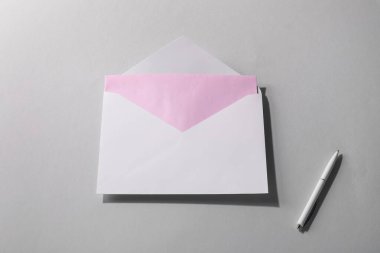 Gri arkaplanlı, üzerinde harf ve kalem olan kağıt bir zarf. Tasarım için model