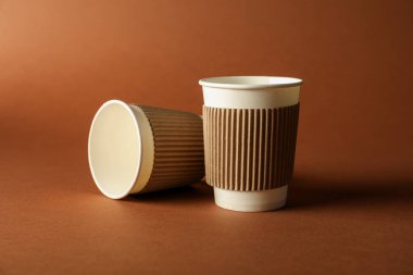 Kahverengi arka planda kağıt bardaklar. Tasarım için model