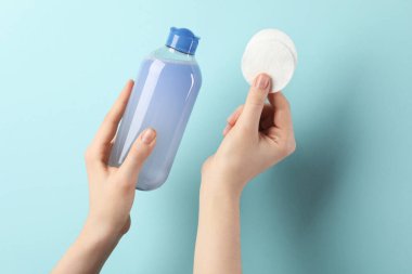 Mikiler suyu ve açık mavi arka planda temiz pamuk pedleri olan kadın, yakın plan.