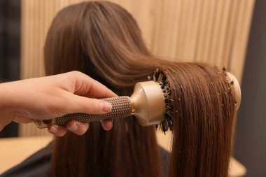 Kuaför, kuaför kuaförü kuaföründe müşterinin saçını tarıyor.