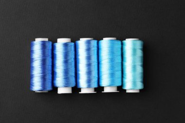 Siyah arkaplanda renkli dikiş iplikleri, düz yatıyordu